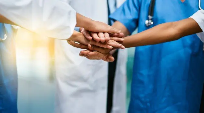 Shot of a group of unrecognisable medical practitioners joining their hands together in unity